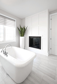 A bathroom with light grey walls and white boards along one side of the wall featuring a fireplace on the white wall.