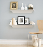 Light grey wall with two white boards on the wall and white moulding on the bottom of the wall