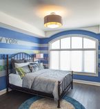 Chambre à coucher avec bande bleue et blanche peinte sur le mur avec plintes et cadrages blancs en bordure d'une grande fenêtre