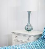 Close up photo of white wainscot wall treatment with nightstand and lamp