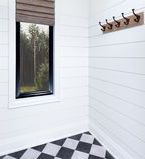 Wall mounted coat rack on white shiplap treated wall with window and casing