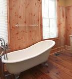Claw foot bathtub with natural wood wall treatment and baseboard