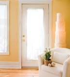 Yellow wall entrance way with white casing around the door and window